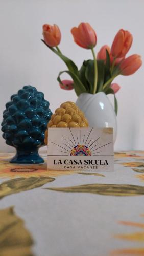 un tavolo con un vaso con fiori e un cartello di La Casa Sicula a Capri Leone