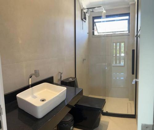 CamassariにあるCasa Alto Padrão Praia Guarajubaの白い洗面台とシャワー付きのバスルーム