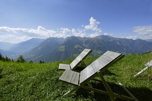 a bench sitting on top of a grassy hill at Ferienwohnungen Wiesbauer in Schenna