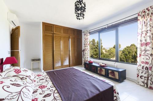 1 dormitorio con 1 cama grande y ventanas grandes en Castell Bohio, en Urbanización Ses Palmeres