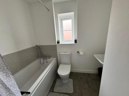 a bathroom with a toilet and a tub and a window at The willows in Hardingstone