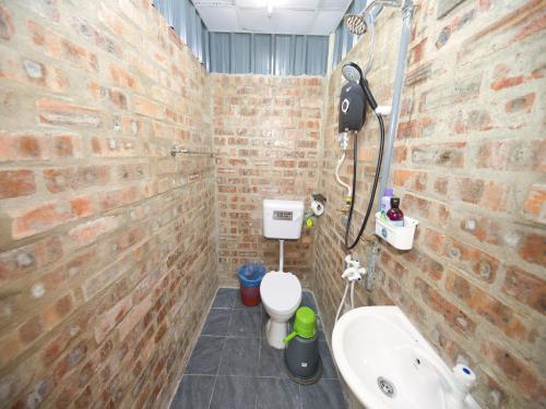 OYO 90960 Rajawali D'cabin Chalet Roomstay في كوالا ترغكانو: حمام مسور من الطوب مع مرحاض ومغسلة
