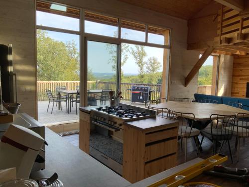une cuisine avec une cuisinière et une table avec des chaises dans l'établissement Maison bois, proche Sarlat, à Domme