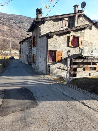 an old stone building with a road in front of it at La casetta di campagna in Mazzo di Valtellina