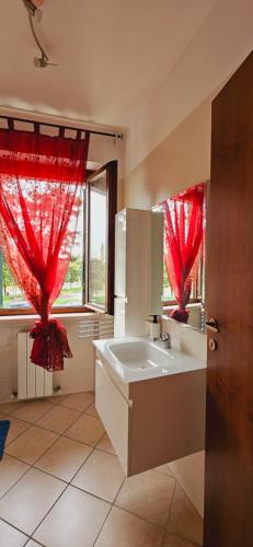 La salle de bains est pourvue de rideaux rouges et d'un grand lavabo. dans l'établissement GM Apartment, à Vérone