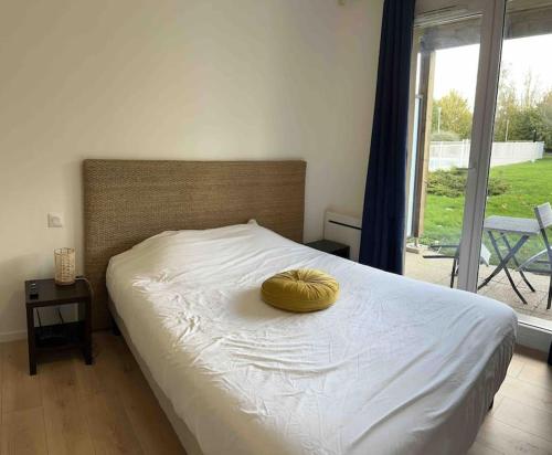 - un lit avec un oreiller jaune au-dessus dans l'établissement Studio cosy ac piscine proche de Honfleur - 10 min, à Équemauville