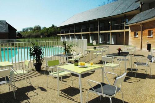 un patio avec tables et chaises à côté d'une piscine dans l'établissement Studio cosy ac piscine proche de Honfleur - 10 min, à Équemauville