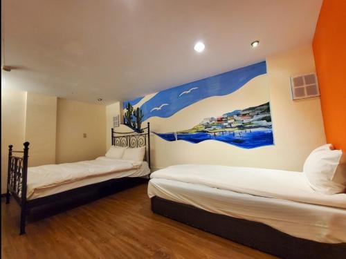 two beds in a room with a painting on the wall at Old Street Seaview Homestay in Jiufen