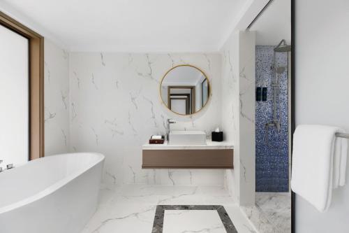 La salle de bains blanche est pourvue d'une baignoire et d'un miroir. dans l'établissement Four Points by Sheraton Boracay, à Boracay