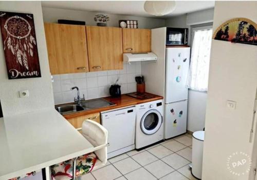 uma cozinha com um frigorífico e uma máquina de lavar e secar roupa em Appartement cosy et lumineux à St Estève avec belle vue em Saint-Estève