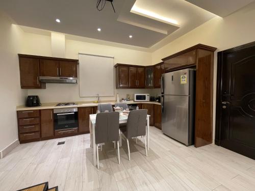 a kitchen with a table with chairs and a refrigerator at شقق خاصه بطابع حديث وفندقي - تسجيل ذاتي Private apartments with modern vibes - self checkin in Riyadh