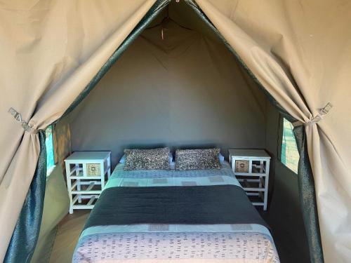 a bed in a tent with two night stands at Soetvlei Tented Farm Camp in Magaliesburg