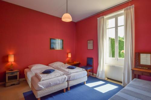 une chambre avec deux lits et un mur rouge dans l'établissement Domaine de Laguneaussan, à Lesparre-Médoc