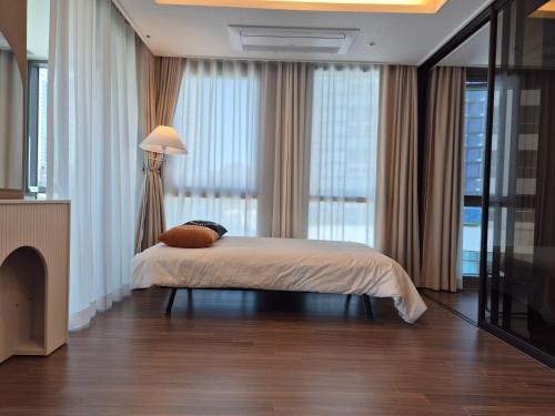 a bedroom with a bed and a large window at Haeundae Family Hotel ARBOL Sunny#ocean view in Busan