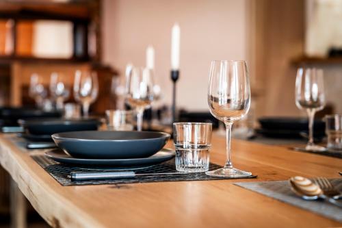 a wooden table with wine glasses and plates on it at Gite des Rousses d'Amont - 15 personnes in Les Rousses