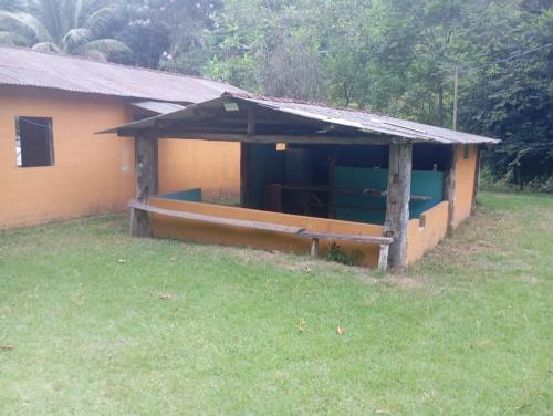 een klein huis met een veranda en een veld bij Camping Casa Velha in Guarapari