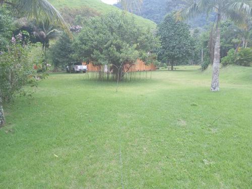 pole trawy z drzewami i płotem w obiekcie Camping Casa Velha w mieście Guarapari
