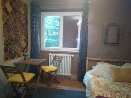 Schlafzimmer mit einem Bett, einem Tisch und einem Fenster in der Unterkunft Les gîtes du Poten'ciel, idéal famille, Bien-être, Massages in Allègre