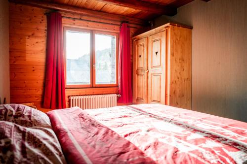 a bedroom with a bed with red curtains and a window at Gite des Rousses d'Amont - 15 personnes in Les Rousses