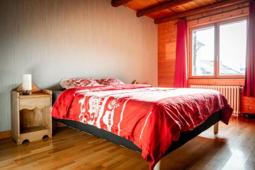 a bedroom with a bed with a red blanket and a window at Gite des Rousses d'Amont - 15 personnes in Les Rousses