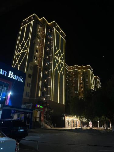 un edificio alto con luces encendidas por la noche en Элитная 2-х комнатная квартира со всеми удобствами, en Shymkent