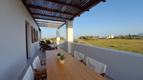 a wooden table on a balcony with a view of a field at Sea breeze houses in Monolithos