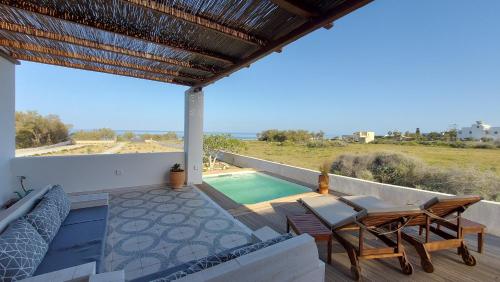 a patio with a table and chairs and a swimming pool at Sea breeze houses in Monolithos