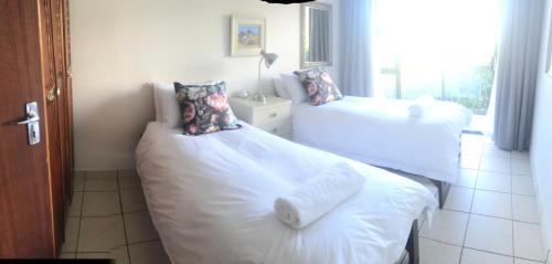 a bedroom with two beds with white sheets and a window at Chandos Apartment Vleesbaai in Vleesbaai