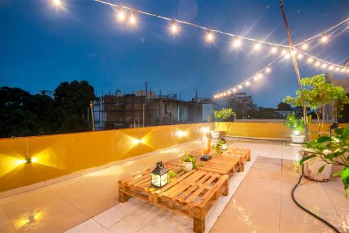 un patio en la azotea con 2 mesas de madera y luces en Cozy Inn en Gurgaon