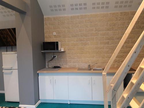 eine Küche mit weißen Schränken und einer Ziegelwand in der Unterkunft Apartement à Theuville-Baigneaux in Theuville