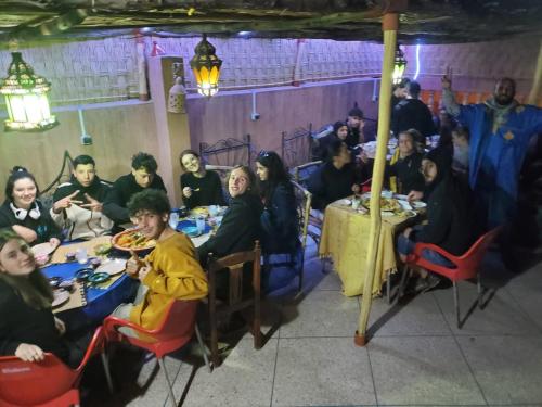 een groep mensen die aan tafel zitten in een restaurant bij Hostel Afgo Rooftop in Ouarzazate