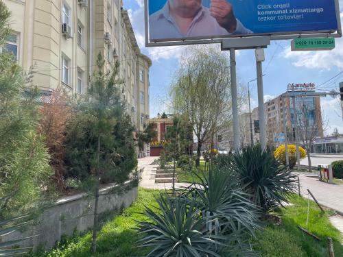 un cartel en medio de una calle con plantas en Cozy apartment, en Samarkand