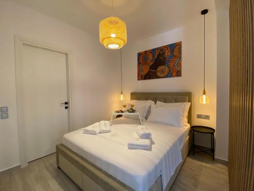 Platinum River Apartments في Potamós: غرفة نوم بسرير ابيض عليها مناشف