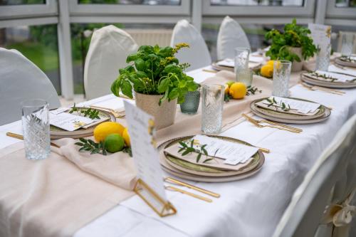 a long white table with plates and plants on it at Kontaktlos Hotel Vintage in Pulheim