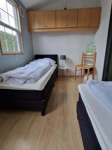 a bedroom with two beds and a chair and a window at Kustverhuur, Groede, Paarlhof 17 in Groede