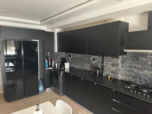 a kitchen with black cabinets and a stone wall at Appartement Luxe F4 Bordj El kiffan in Fort de lʼEau