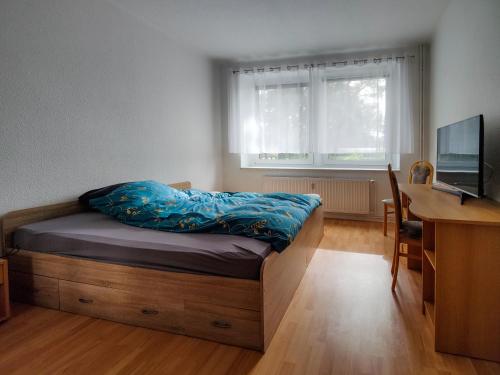een slaapkamer met een bed, een bureau en een computer bij Ferienwohnung Jänschwalde in Jänschwalde Ost