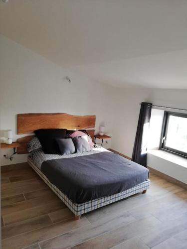 une chambre avec un lit avec une tête de lit en bois dans l'établissement L'oustalou, à Saint-Genest-de-Bauzon