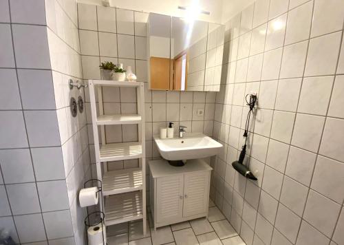 La petite salle de bains est pourvue d'un lavabo et d'un miroir. dans l'établissement Schölerberg Apartment mit Tiefgaragenparkplatz und Kingsize-Bett, à Osnabrück