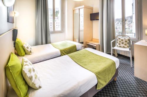 a hotel room with two beds and a chair at H&ocirc;tel Notre Dame de France in Lourdes