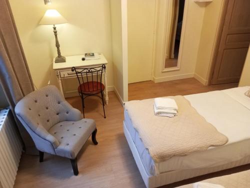 a bedroom with a bed and a chair and a table at Logis Hôtel Louise de Savoie in Blois