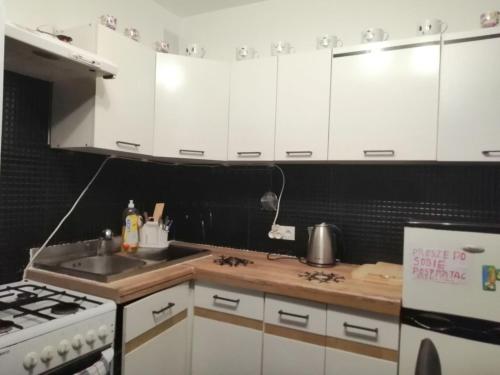 a kitchen with white cabinets and a sink and a stove at Apartamenty na doby in Siedlce
