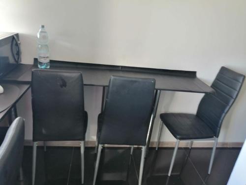 three chairs and a desk with a bottle of water at Apartamenty na doby in Siedlce