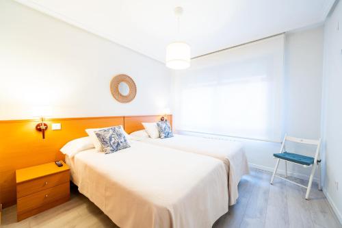 a bedroom with two beds and a chair in it at Apartamentos GO - Génova Parquesol - Parking Gratuito-Zona libre de bajas emisiones in Valladolid