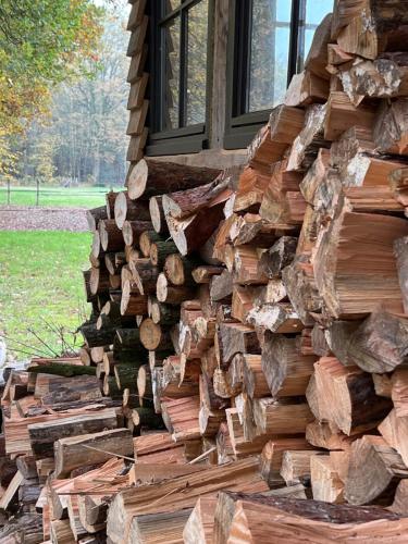 a pile of wood on the side of a house at Gehele accommodatie met boshuisje en 3 woonwagens in Ranst