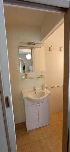 une salle de bain blanche avec un lavabo et un miroir dans l'établissement Gîte ensoleillé, au calme, proche Montségur, à Fougax-et-Barrineuf