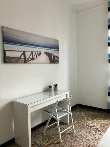 a white desk with a chair and a painting on the wall at Brignole Home in Genova