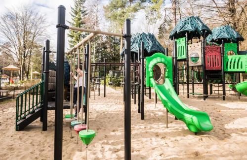 a playground with a green slide in the sand at Chalet de Bosrand 404, unieke rustige plek met veel privacy aan de bosrand van vakantiepark op de Veluwe in Beekbergen