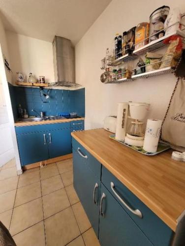 une cuisine avec des placards bleus et un comptoir en bois dans l'établissement Appartement 3 à 4 personnes, à Canet