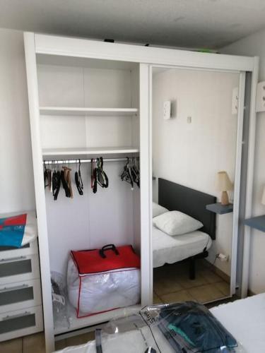 Cette chambre comprend un placard avec une valise rouge. dans l'établissement Appartement 3 à 4 personnes, à Canet